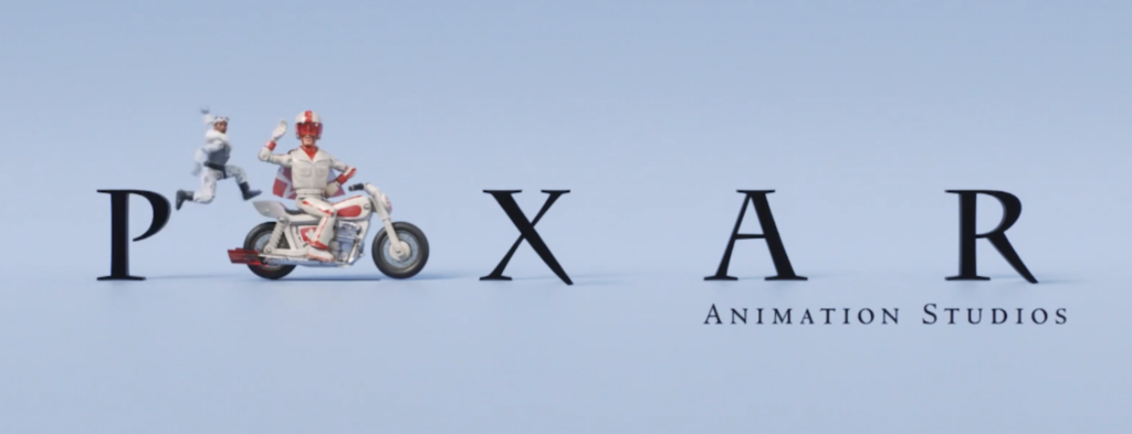 Pixar logo variation featuring Duke Caboom on his motorcycle, joined by Combat Carl Soldier giving a high-five, set against a light blue background.